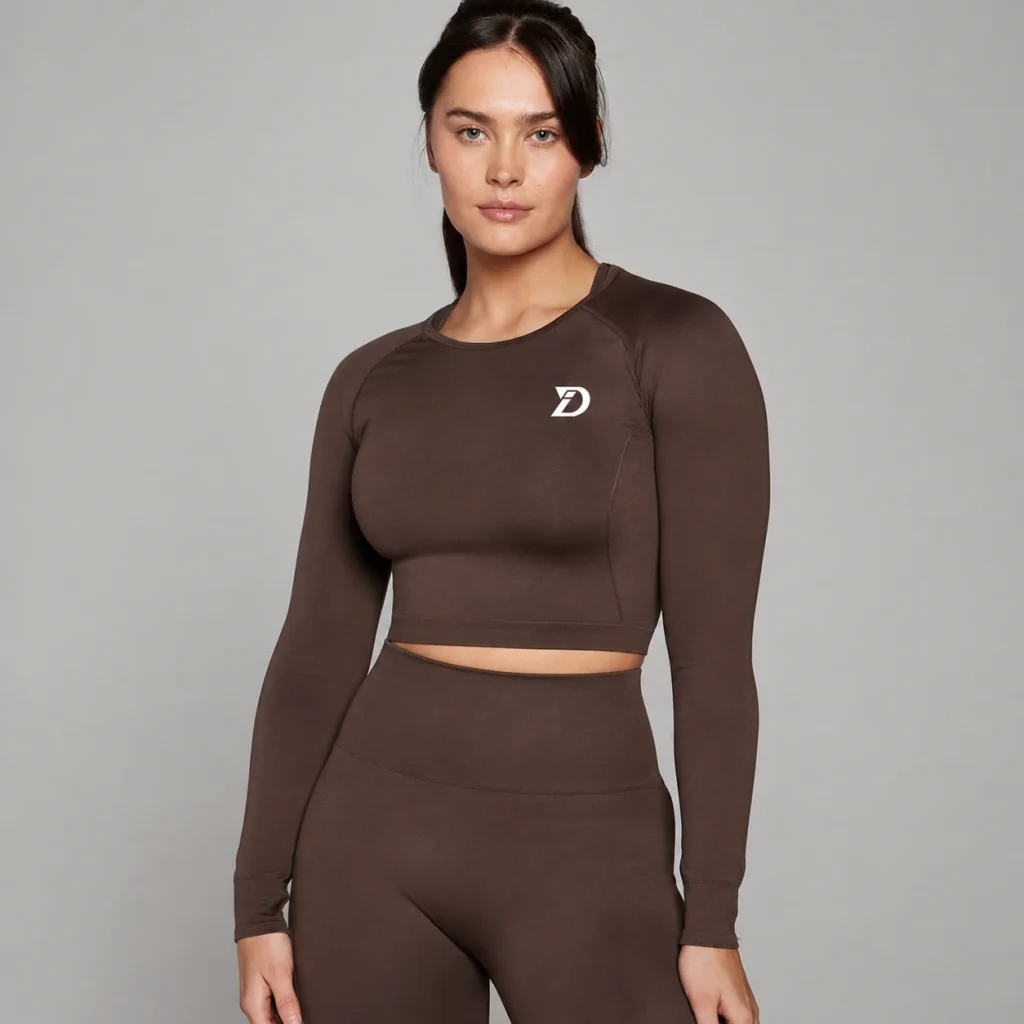 Woman wearing a brown long-sleeve athletic crop top with matching high-waisted leggings.