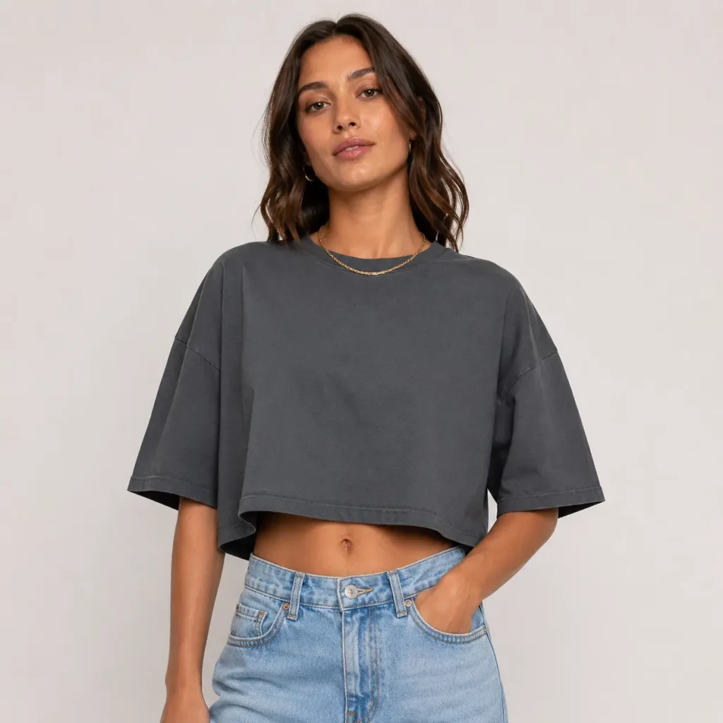 Woman wearing a charcoal oversized cropped T-shirt with light blue jeans against a plain studio background.